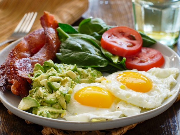 Premium Photo  Keto breakfast plate with eggs bacon and mashed avocado