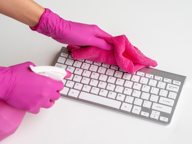 手術用手袋をした人がキーボードを消毒している 無料の写真