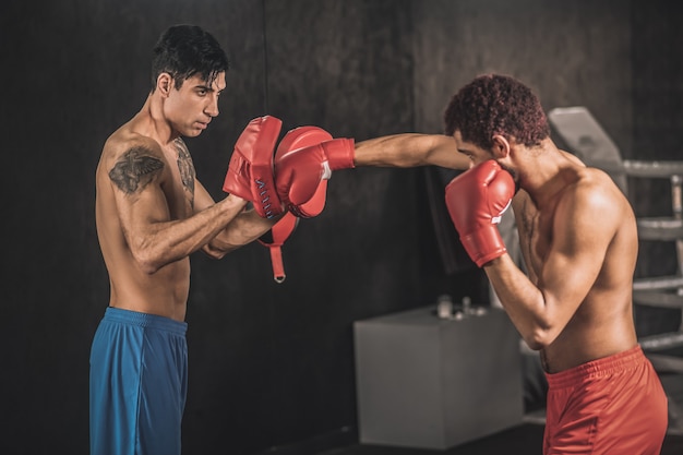 Premium Photo | Kickboxing. young men training in a gym and looking ...