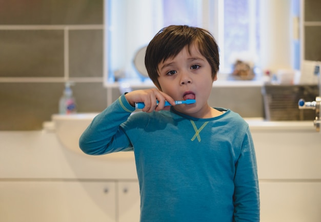 Kid brushing teeth and tongue in the bathroom Premium Photo