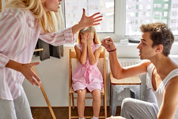 子供の女の子は家で家族の両親の間の喧嘩に苦しんでいます 女性と男性は娘の前で主張します プレミアム写真