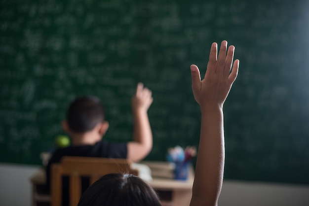 kid raising his hand in classroom  Free Photo