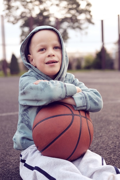 Premium Photo | Kid sitting with basketball ball on basketball street field