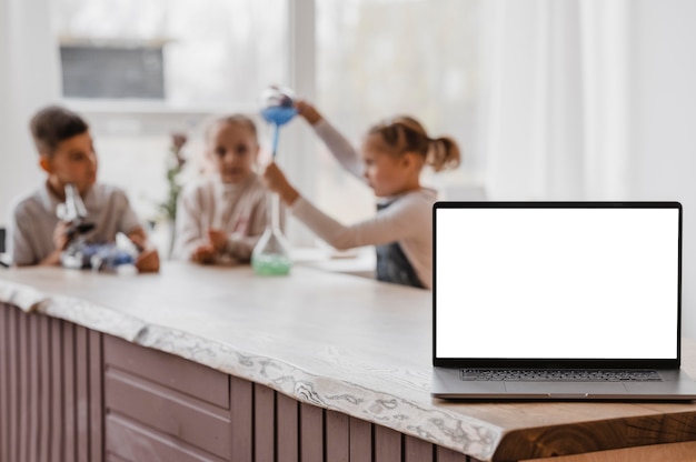 空白の画面のラップトップの横にある化学要素で遊ぶ子供たち 無料の写真