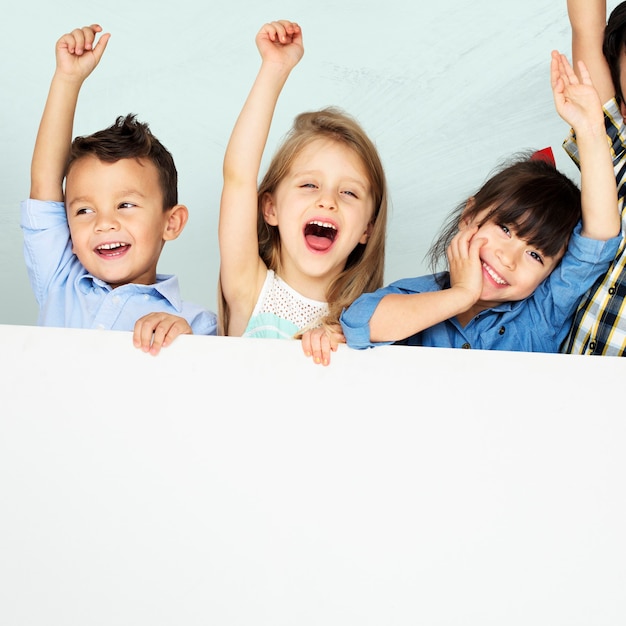 Kids raising arms cheering with mockup board Free Photo