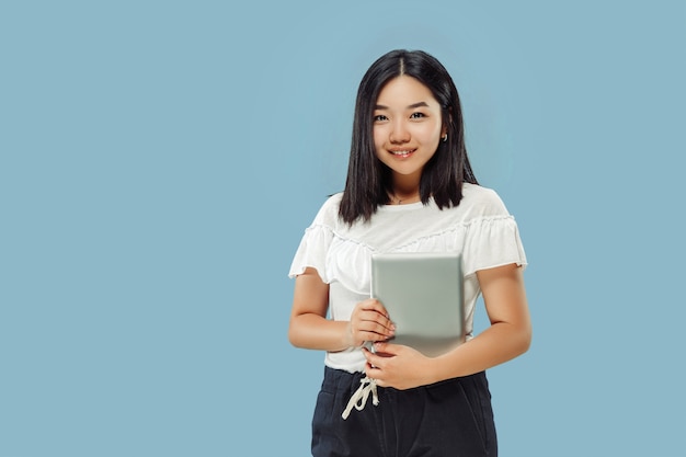 韓国の若い女性の半身像 白いシャツの女性モデル タブレットを持って笑顔 人間の感情 顔の表情の概念 正面図 無料の写真