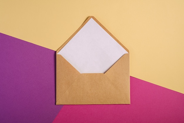 白い空のカード ピンク 紫 クリームイエローの背景 モックアップの空白の手紙とクラフト茶色の紙封筒 プレミアム写真