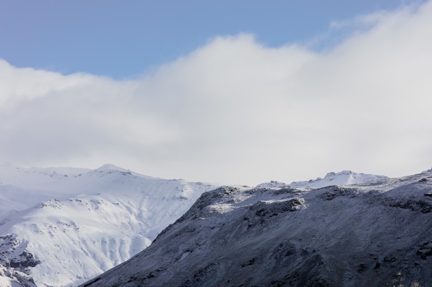Paesaggio Di Montagne Coperte Di Neve Sotto Un Cielo Nuvoloso Blu In Islanda Foto Gratis