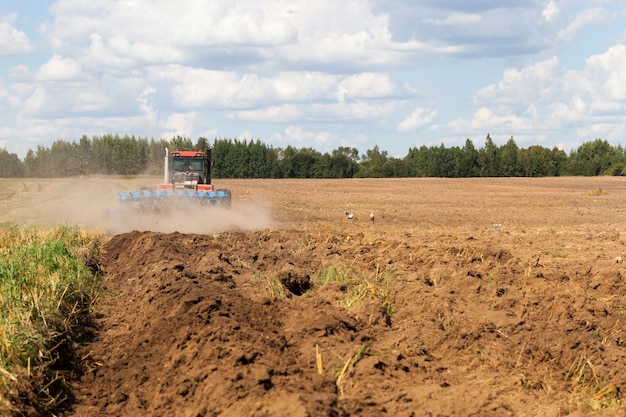 Premium Photo | Large tractor with a plow plows the soil on the field ...