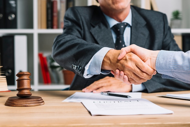 Lawyer and his client shaking hands together over the desk Free Photo