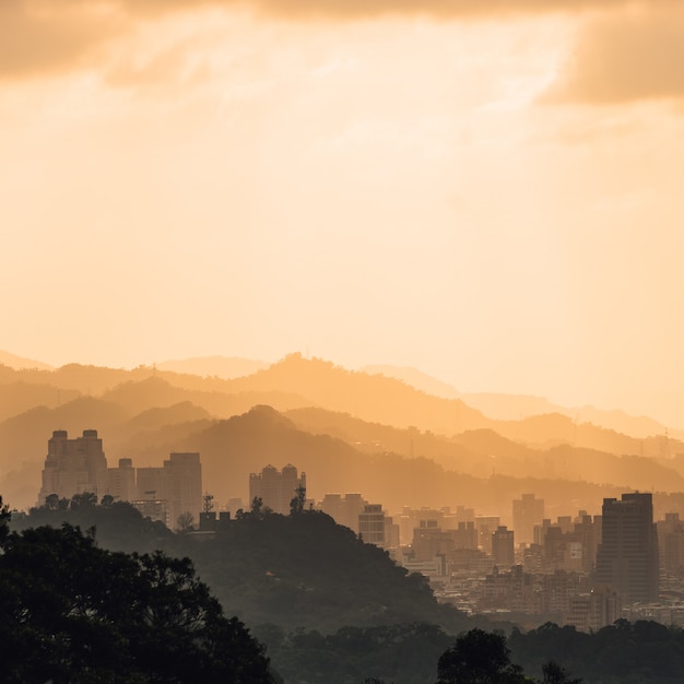 台湾の台北で夕方には太陽が象山からそのビューを下って行くときに台北の街並みと日光の山々の層 プレミアム写真