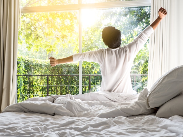 Lazy man happy waking up in the bed rising hands in the morning with fresh  feeling | Premium Photo