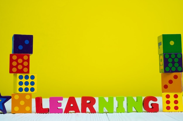 Learning text alphabet and toy square block puzzle on table with yellow background Premium Photo