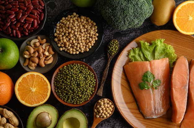 Legumes, fruit and salmon pieces on a wooden plate. Free Photo