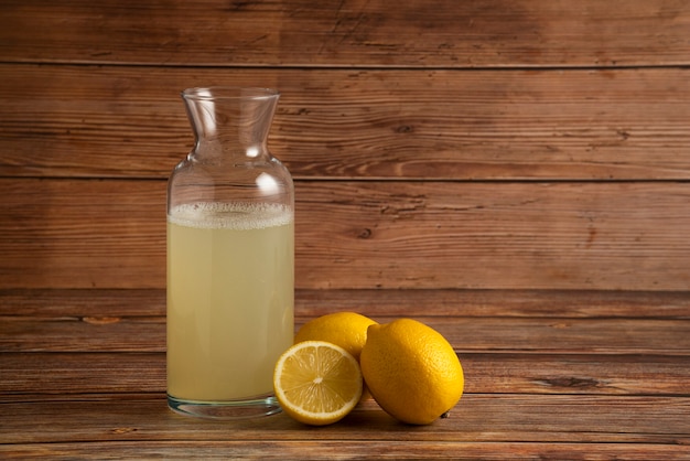 Free Photo Lemon Juice In The Glass Container With Fruits On The Wooden Table