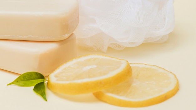 Lemon slices; soap and loofah on colored background Free Photo