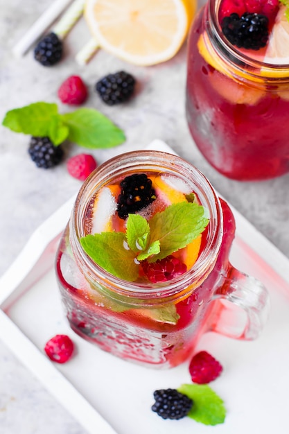 Lemonade with raspberry and blackberry with lemon, mint in mason jar Premium Photo