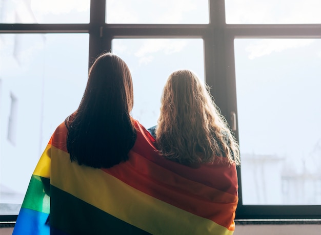 Free Photo Lesbian Sweethearts Wrapped In Lgbt Flag