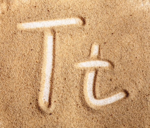 砂の中のt字の英語の手書きのアルファベット プレミアム写真