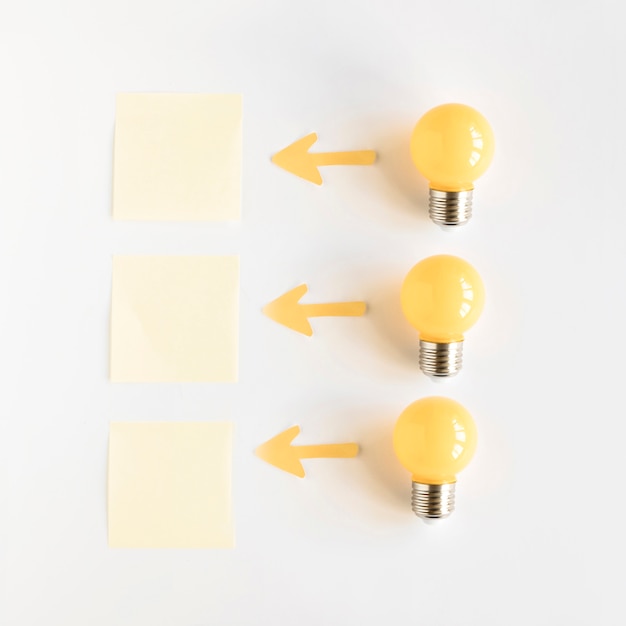 Light bulb near arrow symbols showing direction towards adhesive notes Free Photo