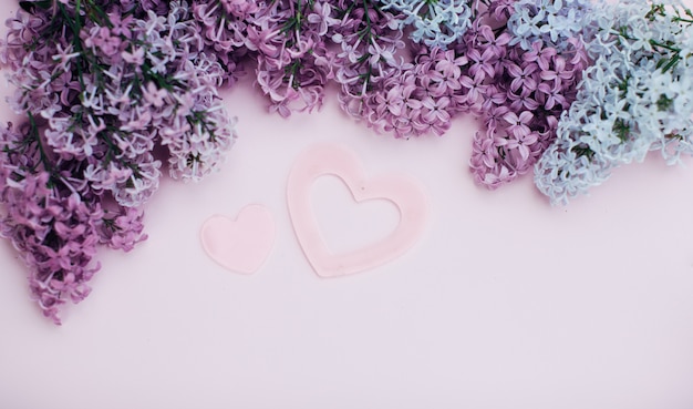 Lilac branches and two pink heart on a light pink background empty space for your text, top view. Premium Photo