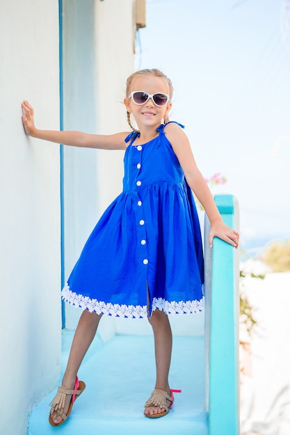 Little adorable girl in dress outdoors in old streets an mykonos. Premium Photo