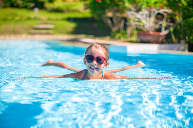 Little adorable happy girl swims in the swimming pool Premium Photo