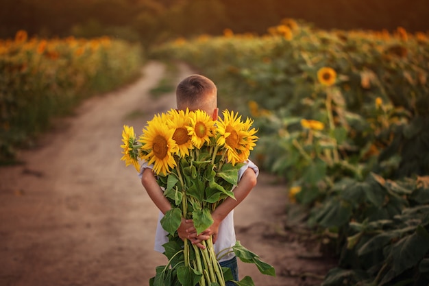 夏の日のひまわりの花束を持ってかわいい子供男の子 プレミアム写真