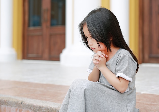 Premium Photo | Little asian girl sitting and praying at the church