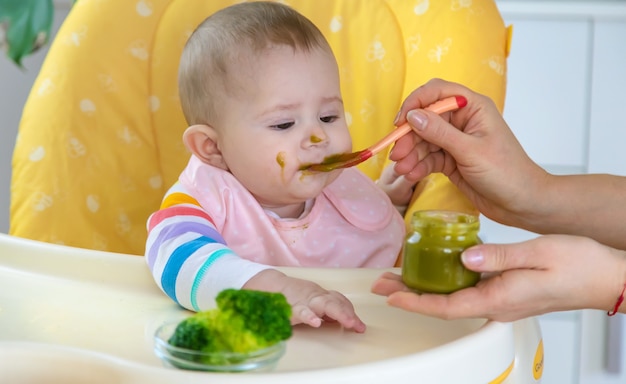 小さな赤ちゃんはブロッコリーの野菜のピューレを食べています セレクティブフォーカス 人 プレミアム写真
