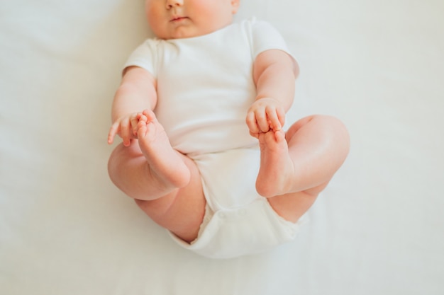 仰向けになって 足に手を伸ばす小さな赤ちゃん プレミアム写真