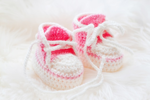 プレミアム写真 小さなベビーシューズ 生まれたばかりの女の子のための手編みの最初のスニーカー かぎ針編みの手作りピンクブーティ