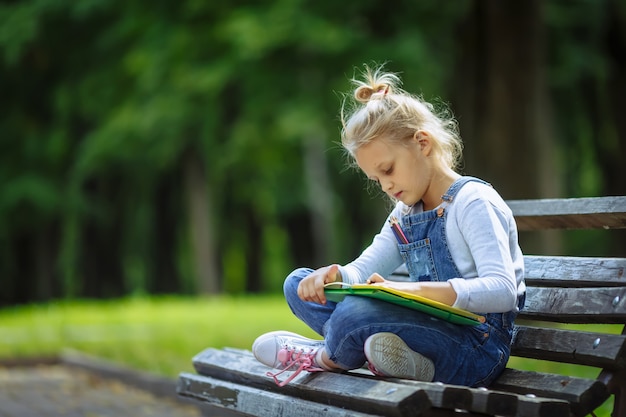 Little Beautiful School Girl Drawing With Colored Pencils Sitting