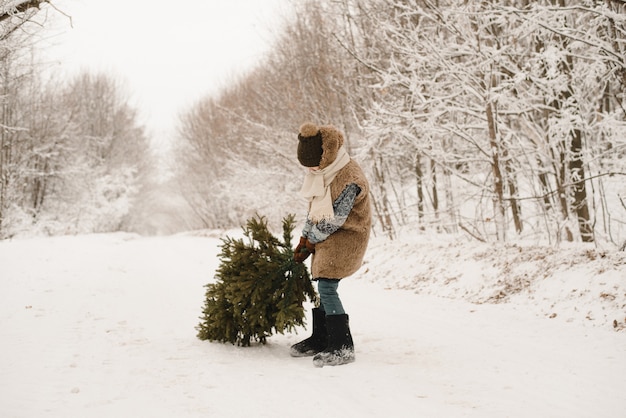 Premium Photo | A little boy carries a christmas tree in an elf costume ...