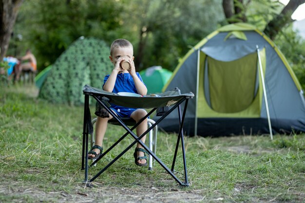 Premium Photo | Little boy eating breakfast outdoor at camping site in ...