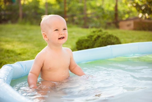 小さな男の子は屋外でお風呂に入ります 小さな男の子が庭で遊んでいます プレミアム写真
