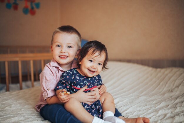 premium-photo-little-brother-3-years-old-and-sister-1-year-hugging-on-bed