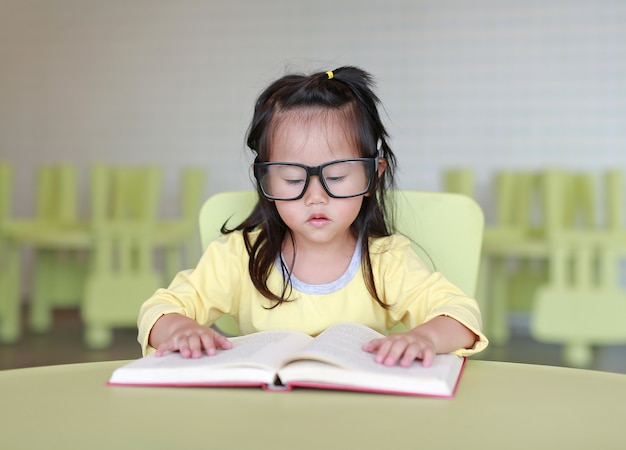 Premium Photo | Little child girl reading book in library