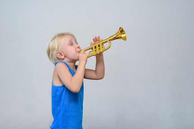 プレミアム写真 おもちゃトランペットを演奏かわいい金髪の少年