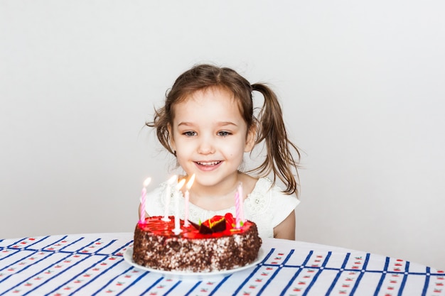 小さな女の子と誕生日ケーキ ろうそくを吹き 願い事をします ケーキとろうそく 誕生日プレゼント 家族 ママとパパ プレミアム写真