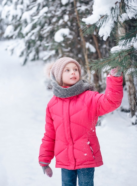 Premium Photo | A little girl in a bright jacket plays in the winter ...