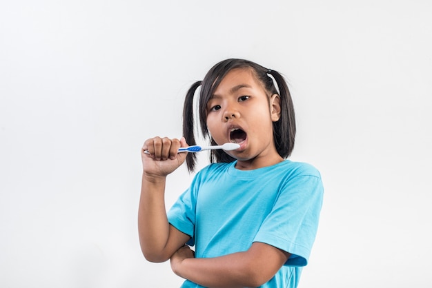 Little girl brushing her teeth in studio shot Free Photo