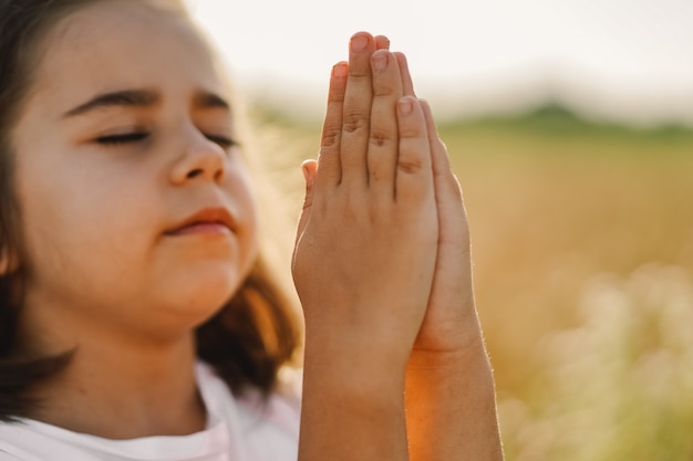 少女は 麦畑で祈りながら目を閉じました 祈りの中で手を組んだ 宗教の概念 プレミアム写真