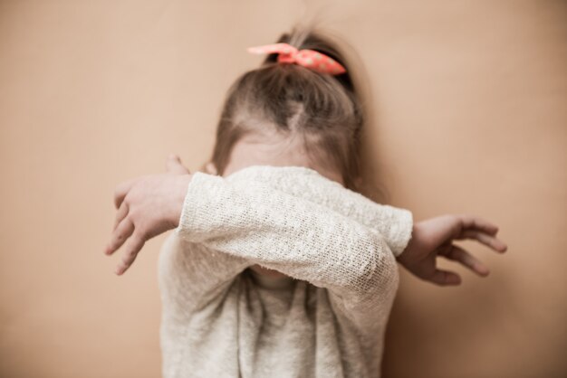 A little girl covers her face with her hands. selective focus Premium Photo