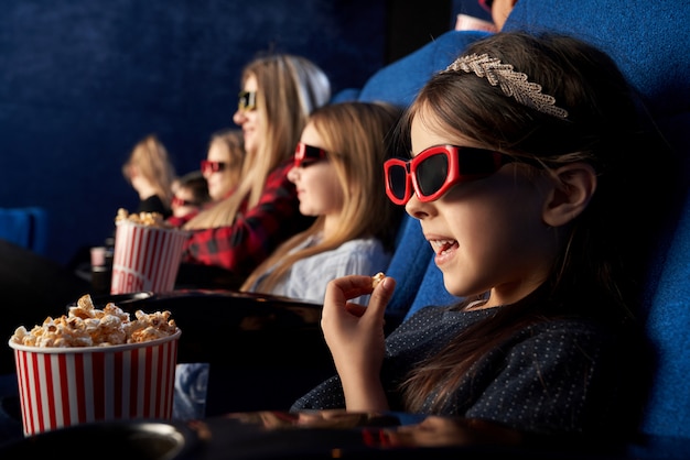 Little Girl Eating Popcorn Watching Cartoon In Cinema Free Photo