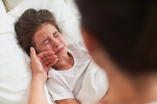 少女は熱でベッドに横たわっている間に病気になりました 子供はとても病気で 彼女は泣いています プレミアム写真