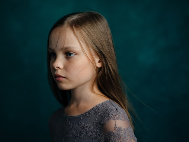 Premium Photo | Little girl in a gray dress on a green background close ...