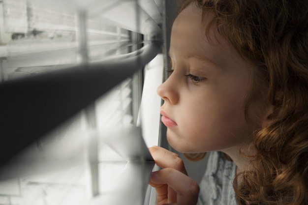 Premium Photo | Little girl looking out the window