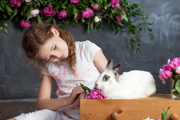 本物のウサギと遊ぶ少女 イースターの子供と白いウサギ 子供やペットが遊ぶ 動物と子供のための楽しさと友情 プレミアム写真