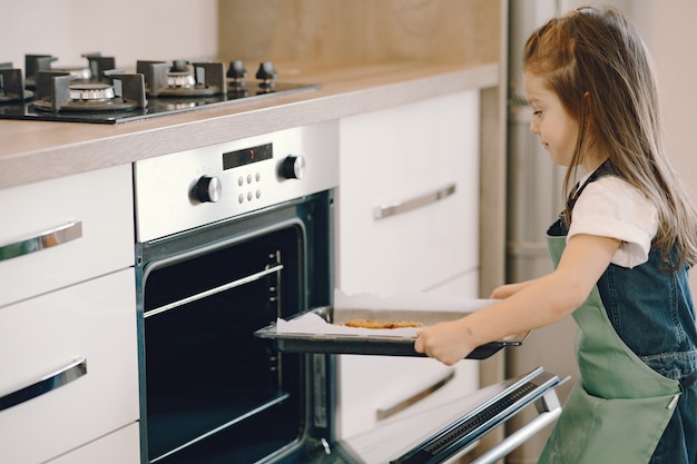 Little girl pulls a cookie tray from the oven Free Photo